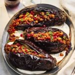 Gefüllte Auberginen mit einer Mischung aus Nüssen, Hackfleisch und Kräutern auf einer Servierplatte.